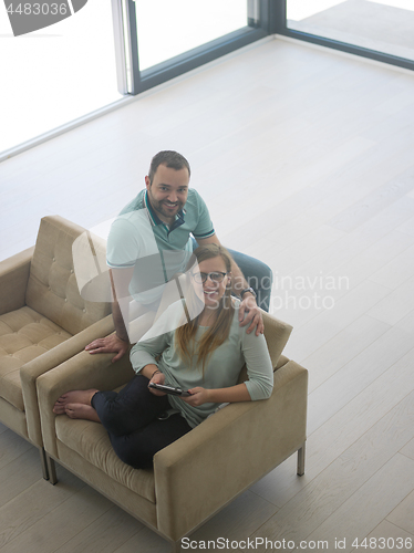 Image of couple relaxing at  home with tablet computers