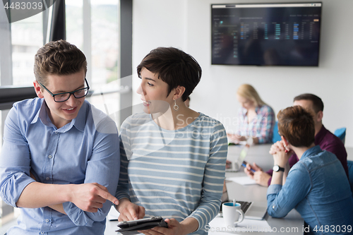 Image of Two Business People Working With Tablet in office