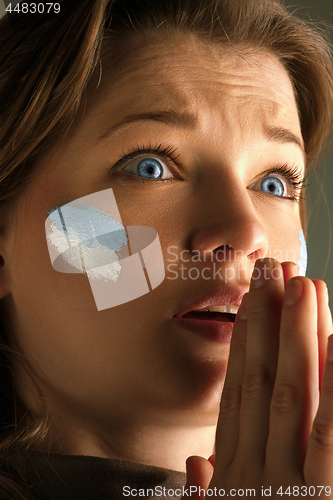 Image of Portrait of a woman with the flag of the Argentina painted on her face.