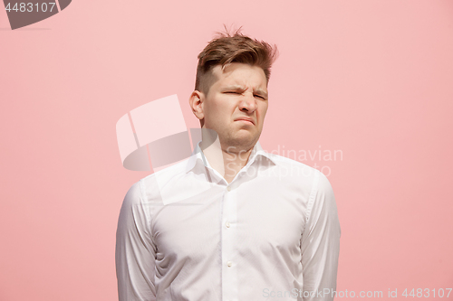 Image of Young man with disgusted expression repulsing something, isolated on the pink