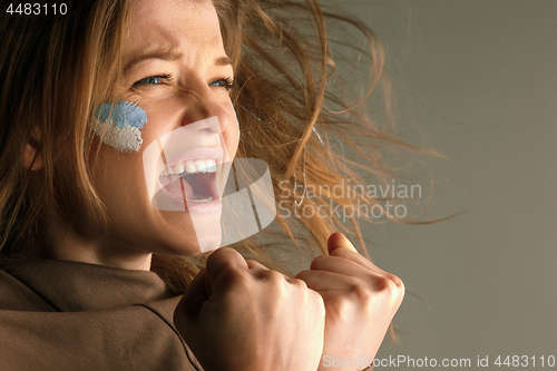 Image of Portrait of a woman with the flag of the Argentina painted on her face.