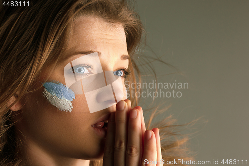 Image of Portrait of a woman with the flag of the Argentina painted on her face.