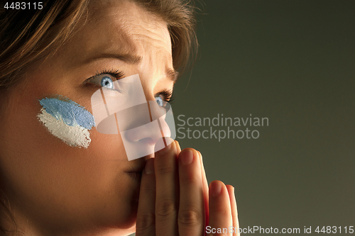 Image of Portrait of a woman with the flag of the Argentina painted on her face.