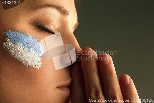 Image of Portrait of a woman with the flag of the Argentina painted on her face.