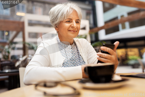 Image of happy senior woman with smartphone at street cafe