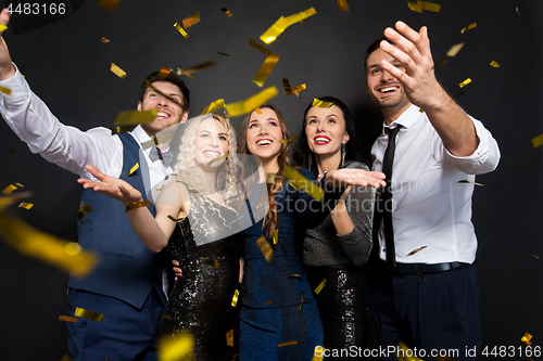 Image of happy friends at party under confetti over black