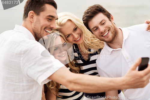 Image of happy friends taking selfie on summer beach