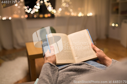 Image of close up of young man reading book at home