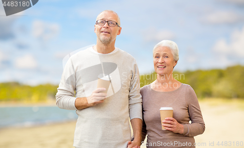 Image of senior couple with takeaway coffee on beach