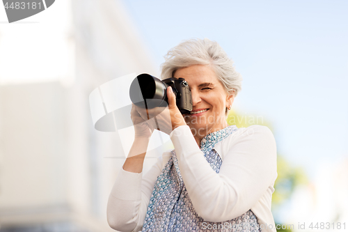 Image of senior woman photographing by digital camera