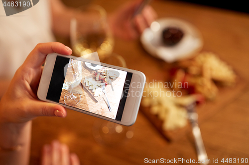 Image of hand picturing food by smartphone at wine bar