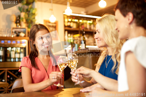 Image of happy women drinking wine at bar or restaurant