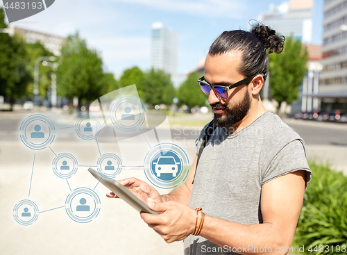 Image of man using car sharing app on tablet pc in city