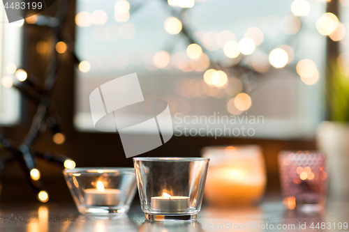 Image of candles burning on window sill with garland lights