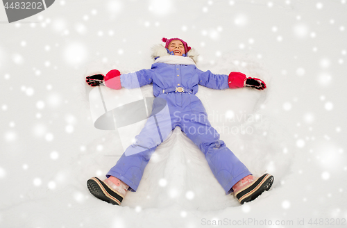 Image of happy little girl making snow angels in winter