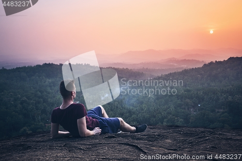 Image of Man contemplation on top of rock