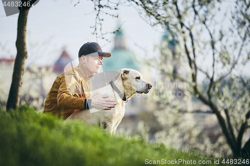 Image of Young man relaxation with dog in public park