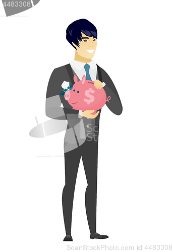 Image of Asian groom holding a piggy bank.