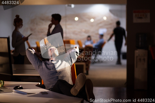 Image of businessman sitting with legs on desk at office