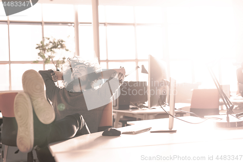 Image of businessman sitting with legs on desk