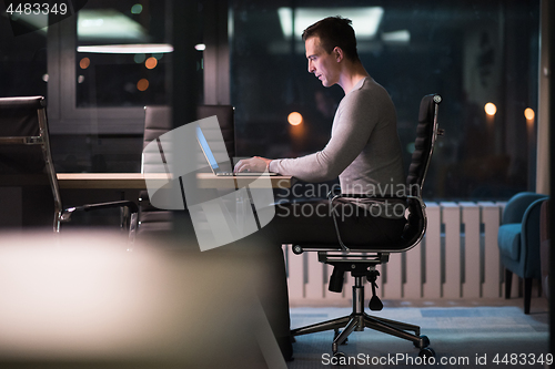 Image of man working on laptop in dark office