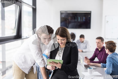 Image of Two Business People Working With Tablet in office