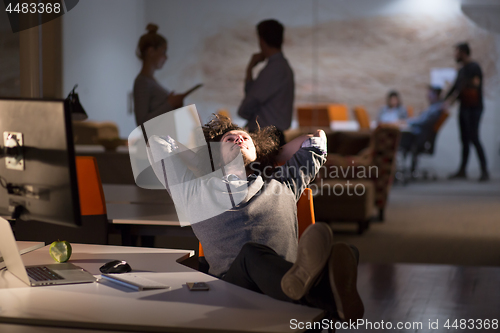 Image of businessman sitting with legs on desk at office