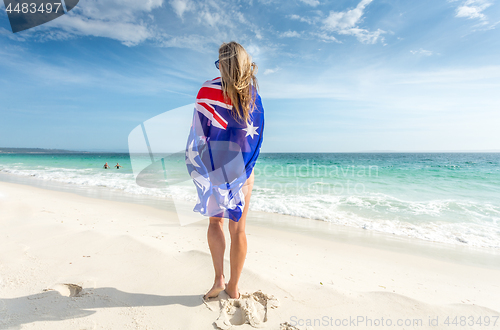 Image of Woman standing on beach with flag wrapped around her