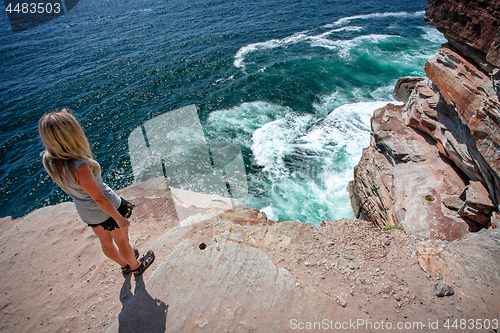 Image of Female takes in the ocean views from cliff top ledge