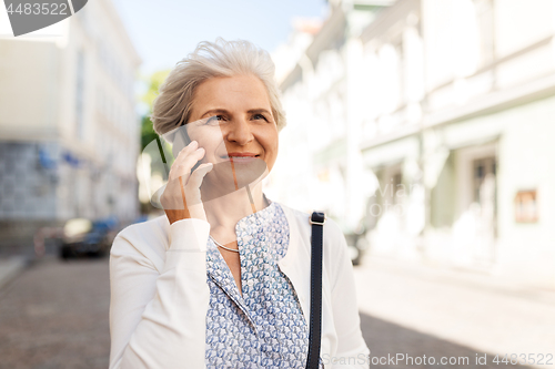 Image of senior woman calling on smartphone in city