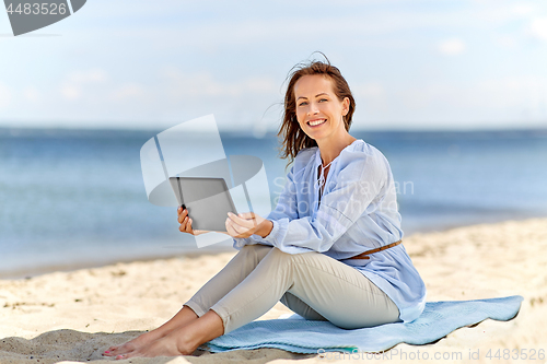 Image of happy smiling woman with tablet pc on summer beach