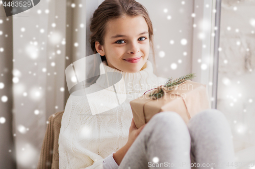 Image of girl with christmas gift sitting at home