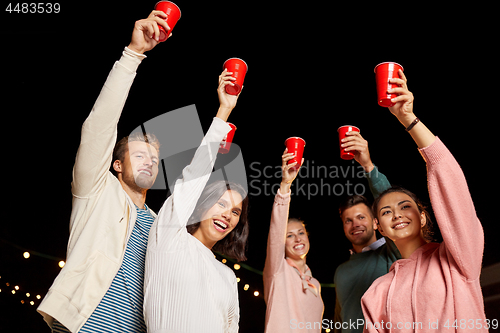 Image of friends toasting party cups on rooftop at night
