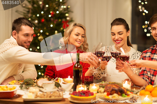 Image of happy friends drinking red wine at christmas party