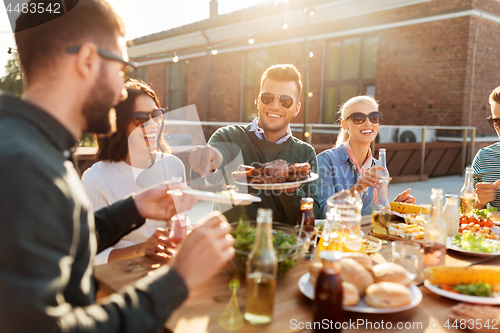 Image of happy friends eating at barbecue party on rooftop