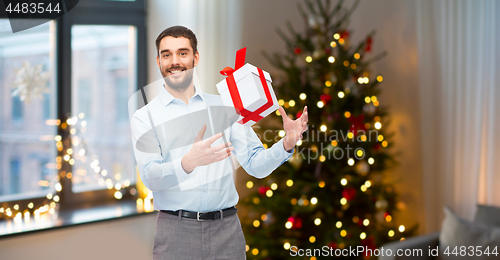 Image of happy man with christmas gift at home