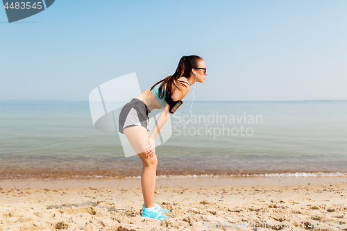 Image of female runner with earphones and arm band on beach