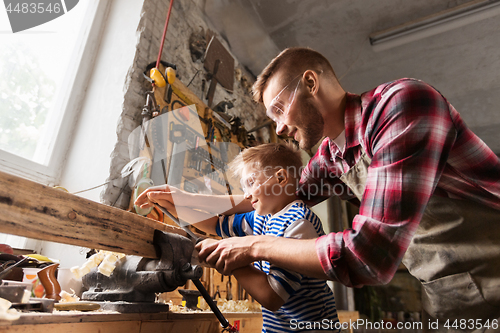 Image of father and son with rasp working at workshop