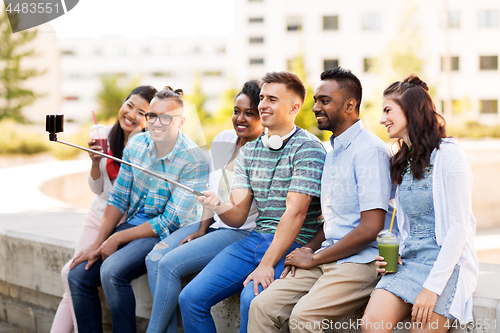 Image of friends taking picture by on selfie stick in city