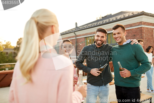 Image of happy friends with drinks hugging at rooftop party