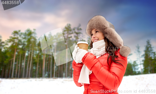 Image of woman in fur hat with coffee over winter forest