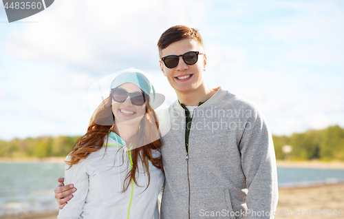 Image of happy teenage couple over beach background