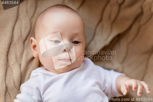 Image of sweet little baby boy lying on knitted blanket