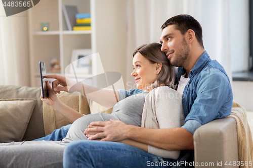 Image of man and pregnant woman with tablet pc at home