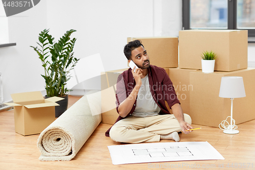 Image of man with blueprint and boxes moving to new home