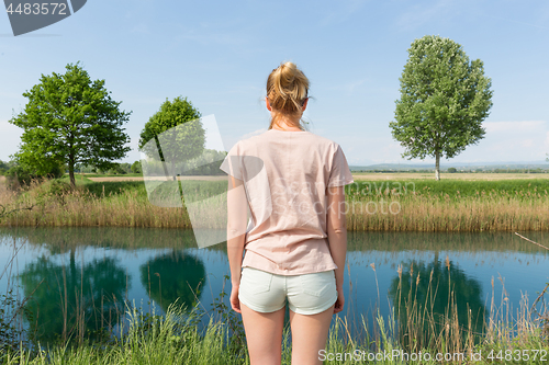 Image of Young woman wearing casual summer clothes enjoying beautiful view of peaceful countryside.