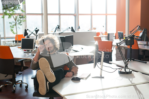 Image of businessman sitting with legs on desk