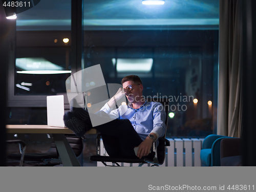 Image of businessman sitting with legs on desk at office