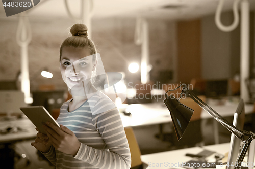 Image of woman working on digital tablet in night office