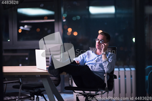 Image of businessman using mobile phone in dark office